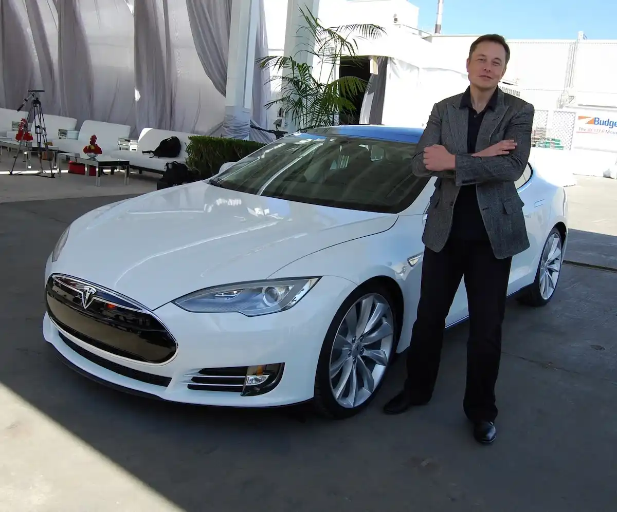 Elon Musk se stal prvním bilionářem světa. Podnikatel Elon Musk stojí vedle bílého elektromobilu Tesla Model S.
