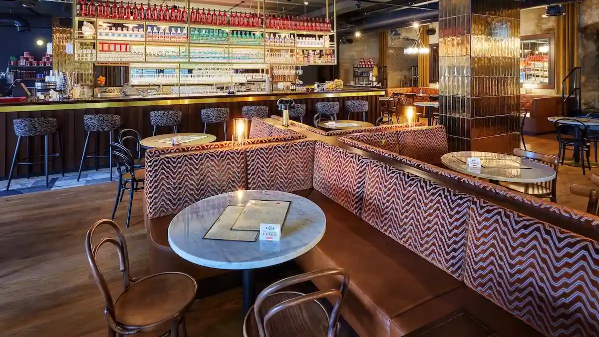 Interiér restaurace L'Osteria s barem, posezením pro hosty a moderním designem.